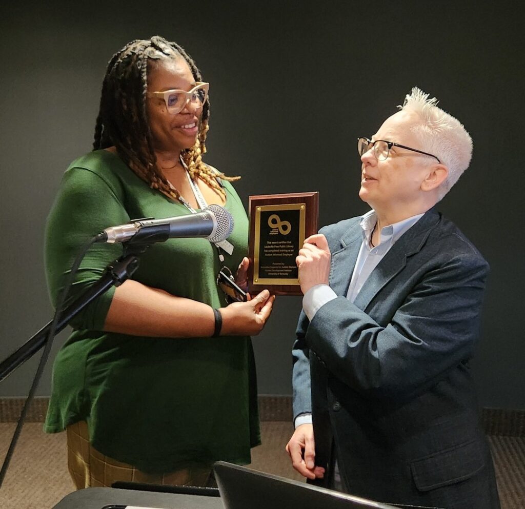 Two people holding a black, gold, and brown plague